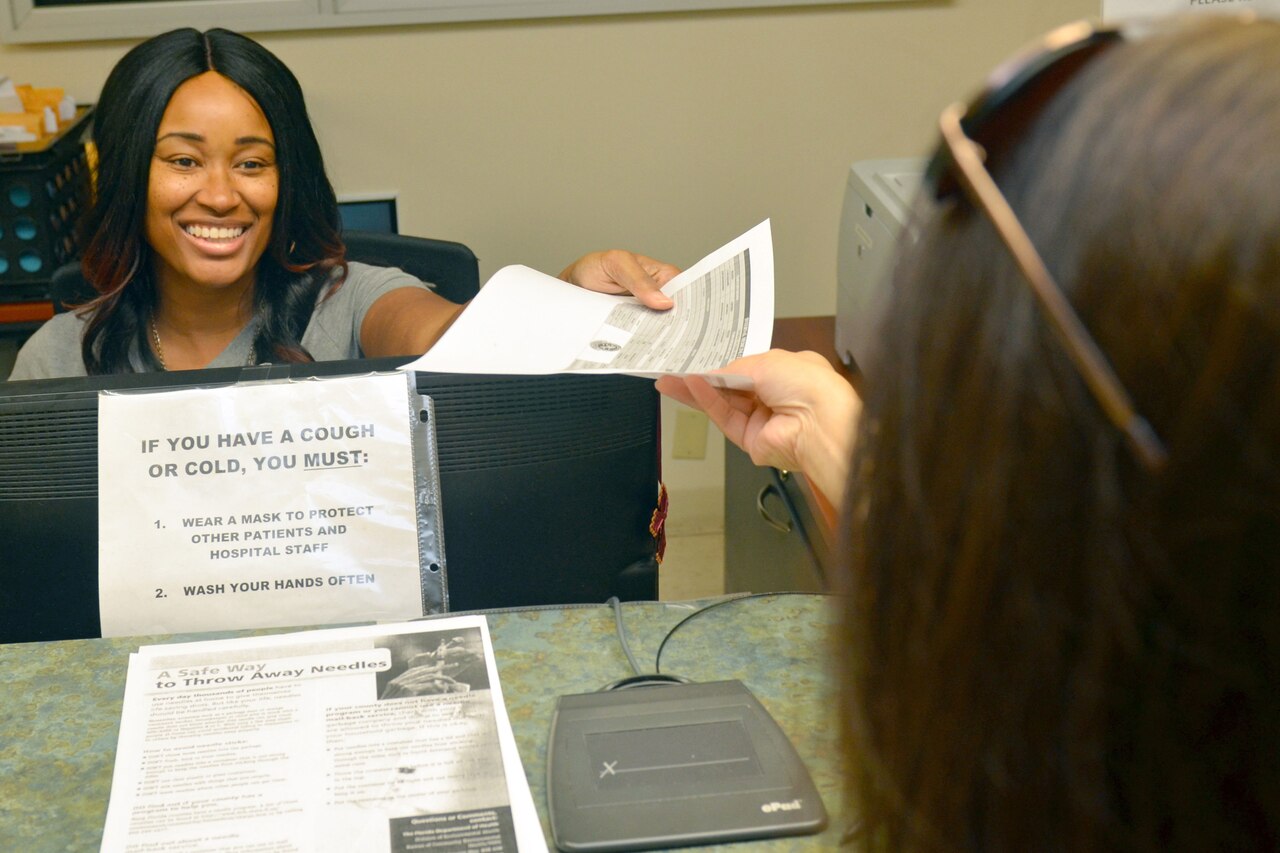 Hospital worker hands paperwork to patient.