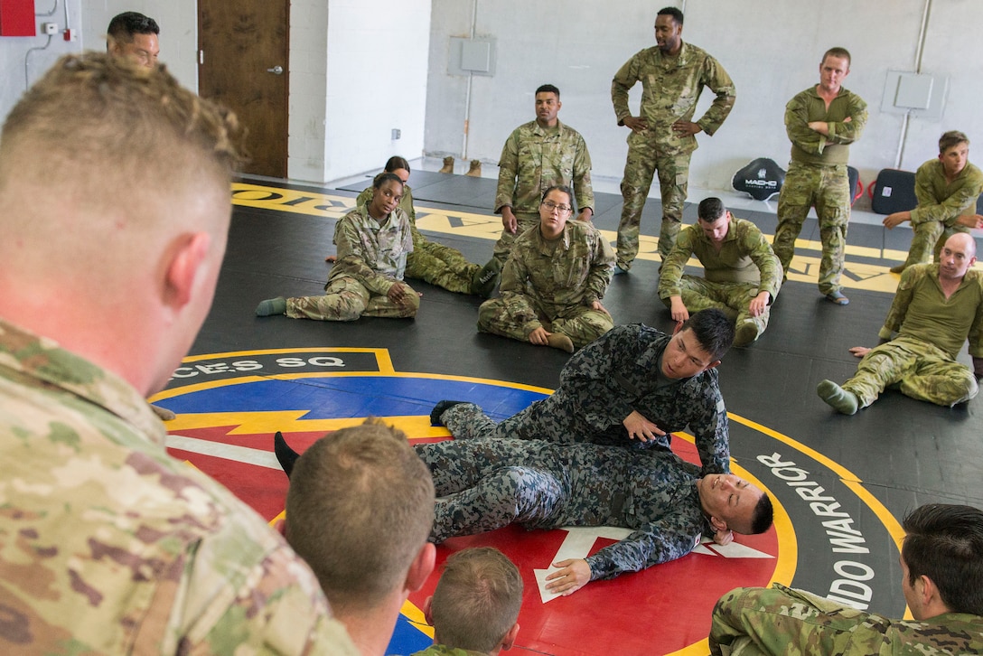 Koku Jieitai (Japan Air Self-Defense Force) Staff Sgt. Hiroki Nishikawa and Staff Sgt. Shiji Miyahara, Base Defense Development Training squadron instructors, demonstrate combative maneuvers to Royal Australian Air Force, U.S. Air Force, and Koku Jietai (JASDF) personnel during Pacific Defender 20-1 at the Pacific Regional Training Center near Andersen Air Force Base, Guam, Feb. 9, 2020.