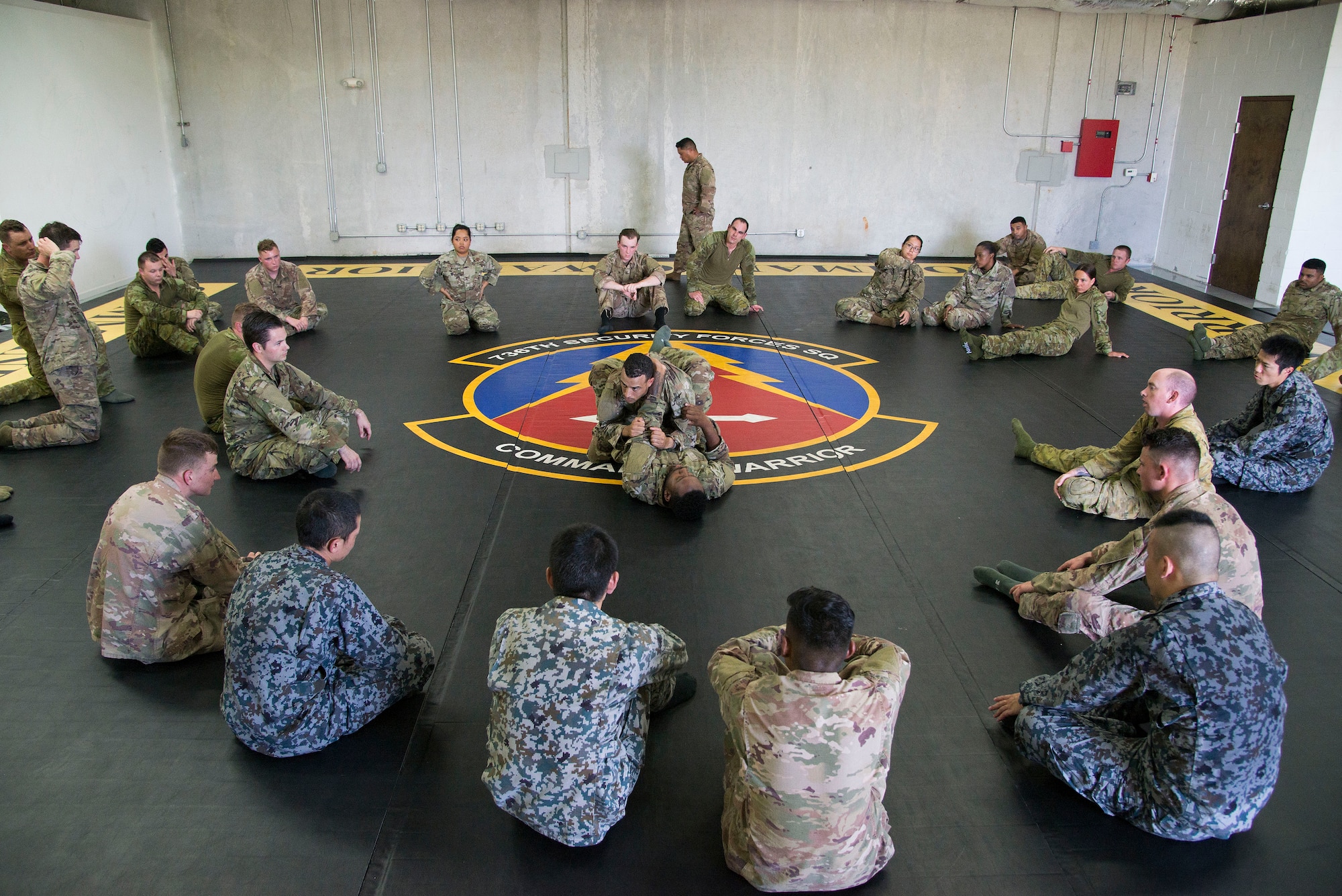 U.S. Air Force Staff Sgt. Okiem Nixon, 736th Security Forces Squadron (SFS) Commando Warrior noncommissioned officer in charge of combat arms, and Staff Sgt. Sean Guillen, 736th SFS Commando Warrior instructor, demonstrate combative maneuvers to Koku Jieitai (Japan Air Self-Defense Force), Royal Australian Air Force, and U.S. Air Force security forces personnel during Pacific Defender 20-1 at the Pacific Regional Training Center near Andersen Air Force Base, Guam, Feb. 9, 2020.