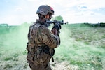Special warfare trainee patrols in the middle of green smoke