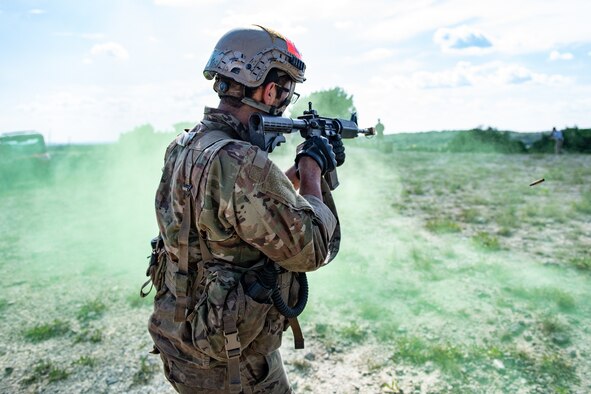 Special warfare trainee patrols in the middle of green smoke