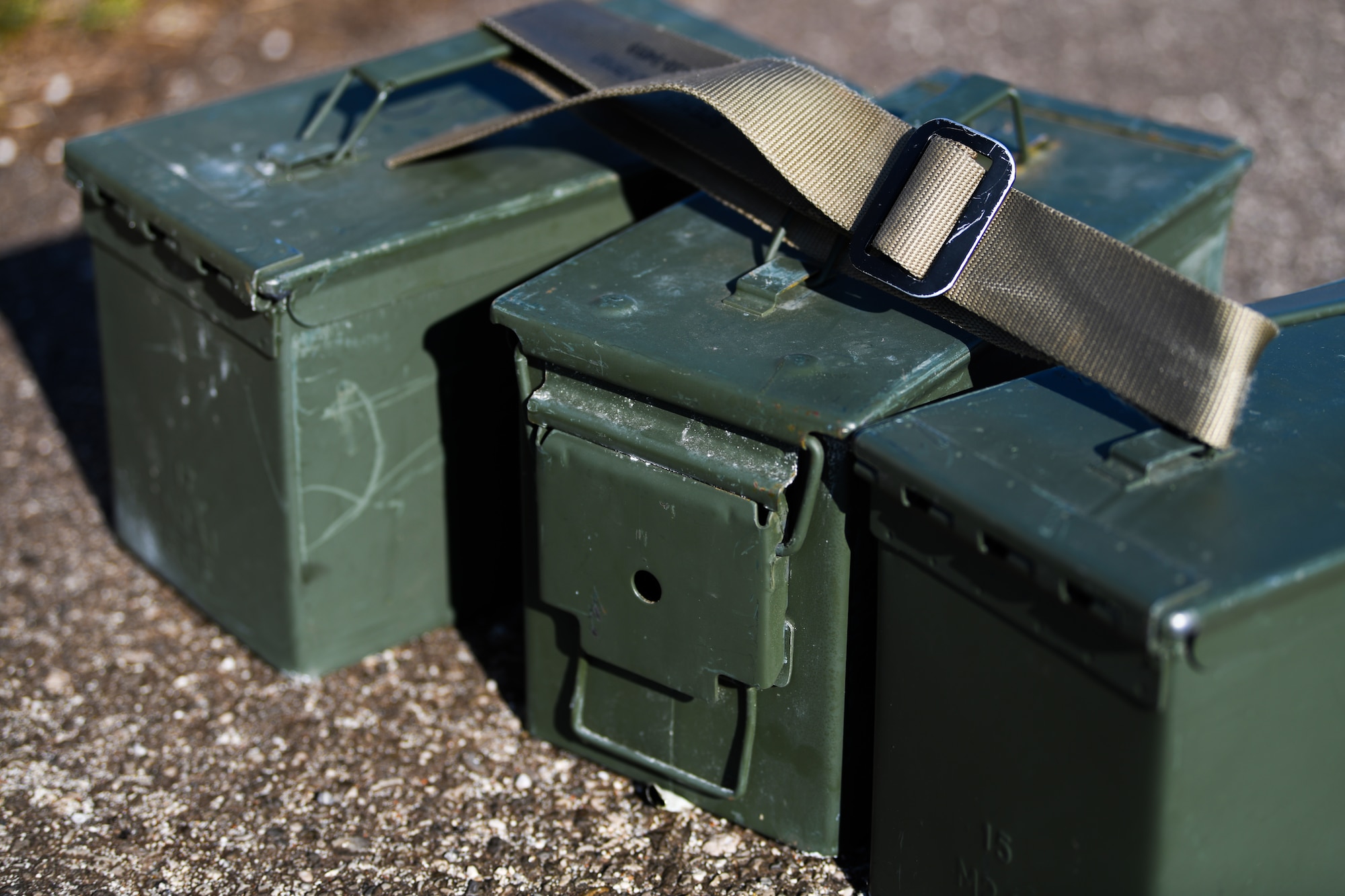 Three full ammunition cans rest on the pavement at Aviano Air Base, Italy, Feb. 14, 2020. Competitors carried ammunition cans in a 400-meter equipment carry during the three day Defender Challenge. (U.S. Air Force photo by Airman 1st Class Ericka A. Woolever)
