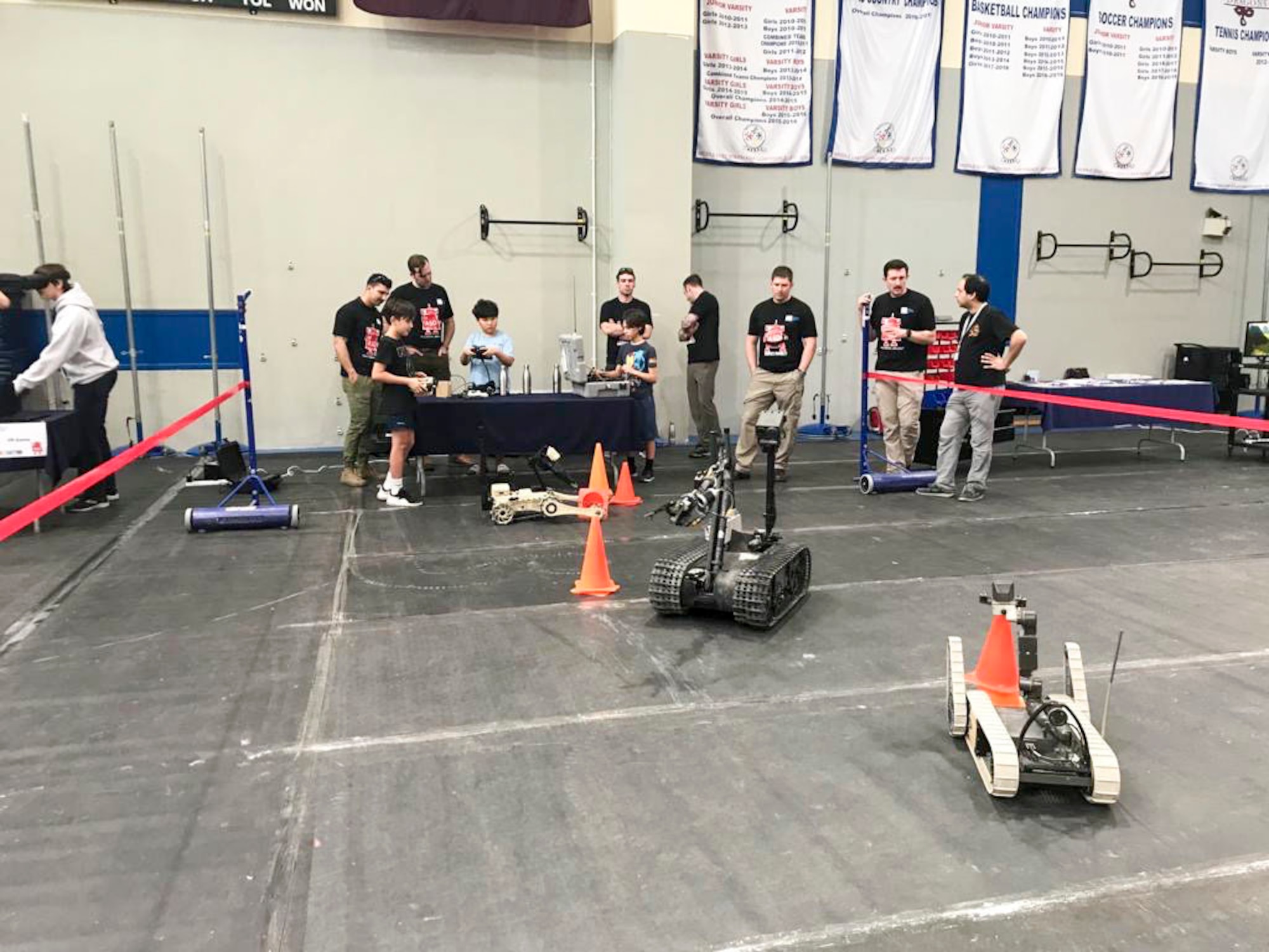 Airmen with 379th Expeditionary Civil Engineering Squadron explosive ordnance disposal team teach students how to operate a bomb defusal robot at American School of Doha’s Maker Faire in Doha, Qatar, on Jan. 25, 2020. EOD Airmen volunteers gave students attending the faire a hands-on experience driving the robots through an obstacle course where they were tasked with using a robot to grab a cone and stack it on another cone. (Courtesy Photo)