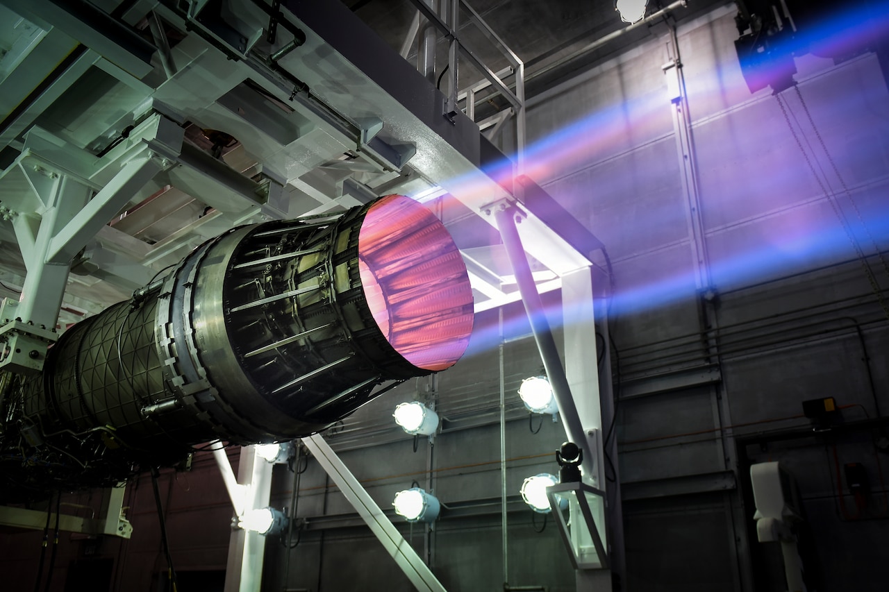 A jet engine in a test facility emits a glowing exhaust.
