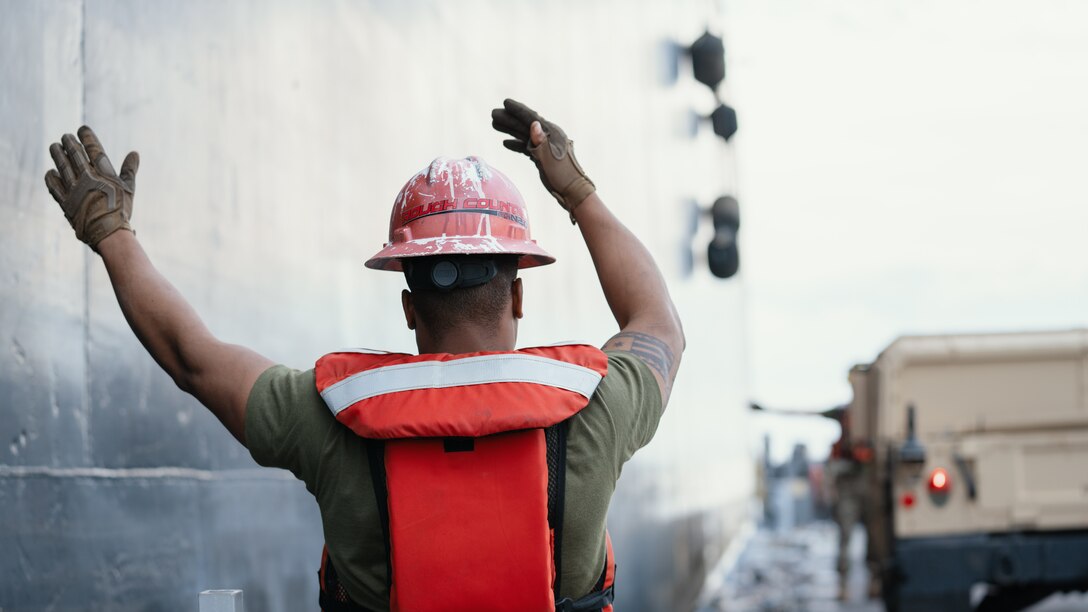 A U.S. Marine acts as a ground-guide after a High Mobility Multipurpose Wheeled Vehicle was offloaded from the USNS 1st Lt. Baldomero Lopez (T-AK 3010) during Maritime Prepositioning Force Exercise 20, Feb. 18, 2020, off the coast of Marine Corps Support Facility Blount Island, Fla. Lighterage allows cargo to be ferried to shore in areas where ports are non-existent or in poor condition and gives the nation's military forces the ability to operate in both developed and undeveloped areas of the world. MPFEX 20 is a military exercise in which Marines and Sailors worked together to offload and process military equipment from a single MPF ship, the USNS 1st Lt Baldomero Lopez (T-AK 3010). The exercise is a rehearsal of the Marines and Sailors’ ability to conduct safe, efficient offloads while in a tactical environment working in close coordination with it’s 2nd and 6th Fleet counterparts to enhance the rapid and scalable deployment of naval expeditionary forces in the European theater. (U.S. Marine Corps photo by Cpl. Rachel K. Young-Porter)