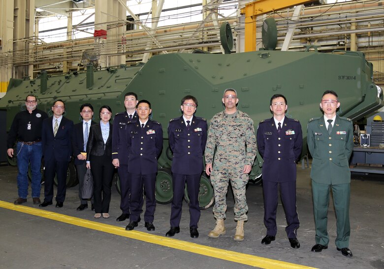 Col. Wilfred Rivera, third from right, Commander, Marine Depot Maintenance Command, Col. Masayuki Endo, second from right, project manager, Acquisition, Technology, and Logistics Agency, Col. Chikao Kuramochi, fourth from right, chief arms section, Logistics Department, Ground Staff Office, and other members of the Japanese Ground Self-Defense Force delegation pose in front of a Assault Amphibious Vehicle during a tour of MDMC’s Production Plant Albany, while at Marine Corps Logistics Base Albany, Georgia, Feb. 18.
