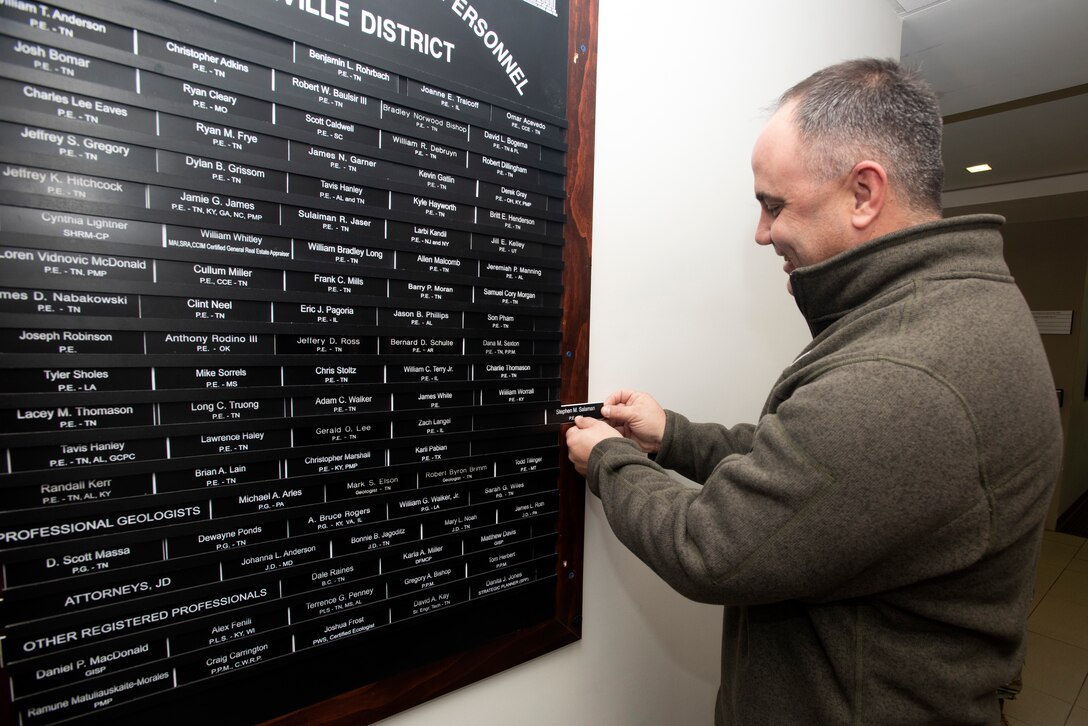 Cory Morgan, U.S. Army Corps of Engineers Nashville District Structural Section chief, affixes a nameplate on behalf of Stephen M. Salaman, structural engineer, onto the "Registered Professional Personnel" board as a record of his achievement during a ceremony Feb. 19, 2020 at the district headquarters in Nashville, Tennessee. Morgan supervises Salaman, who was unable to attend the ceremony, and who passed his exam in the state of Tennessee in October 2019. (USACE Photo by Lee Roberts)