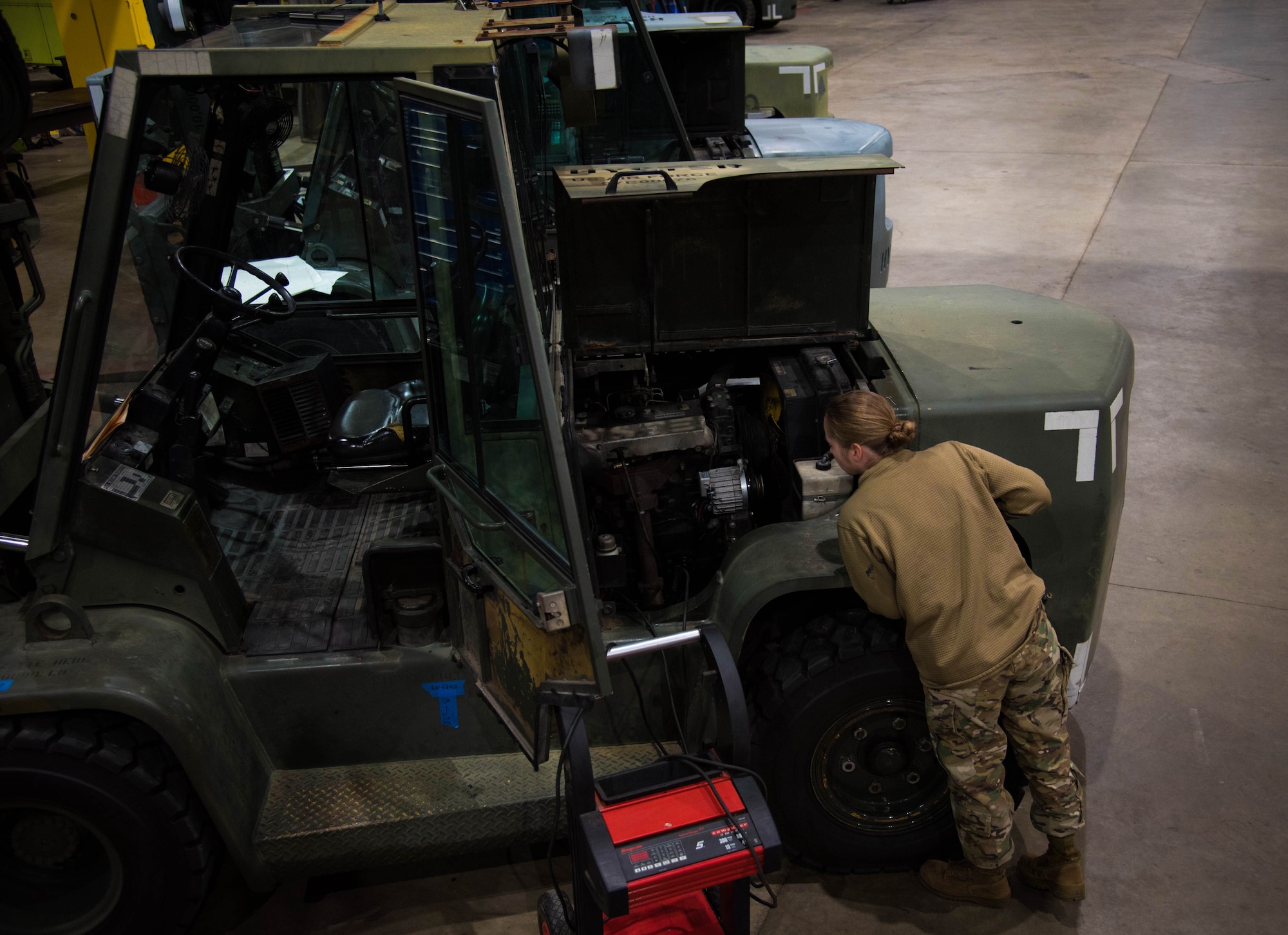 Vehicle maintainer looks at forklift.