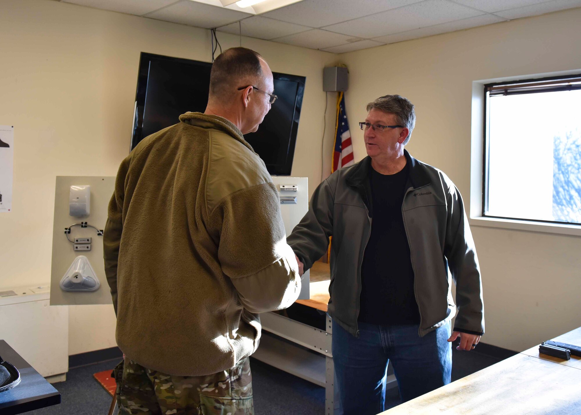 Brig. Gen. Richard Gibbs, Air Mobility Command director of logistics, engineering and force protection, coins David Sherman, 92nd Security Forces Squadron security manager, during a tour at Fairchild Air Force Base, Washington, Feb. 10, 2020. Sherman was coined for his efforts creating a motion-censored alarm system that alerts base security forces when something is tampering with the facility perimeter fence. (U.S. Air Force photo by Airman Kiaundra Miller)