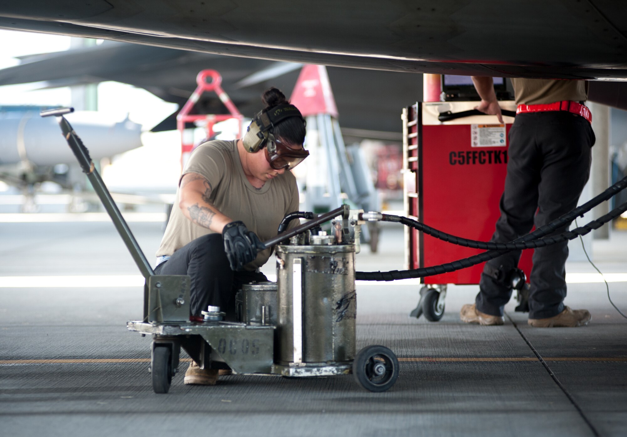Senior Airman Reanna Holcomb, 154th Aircraft Maintenance Squadron assistant dedicated crew chief, services the oil of an F-22 Raptor