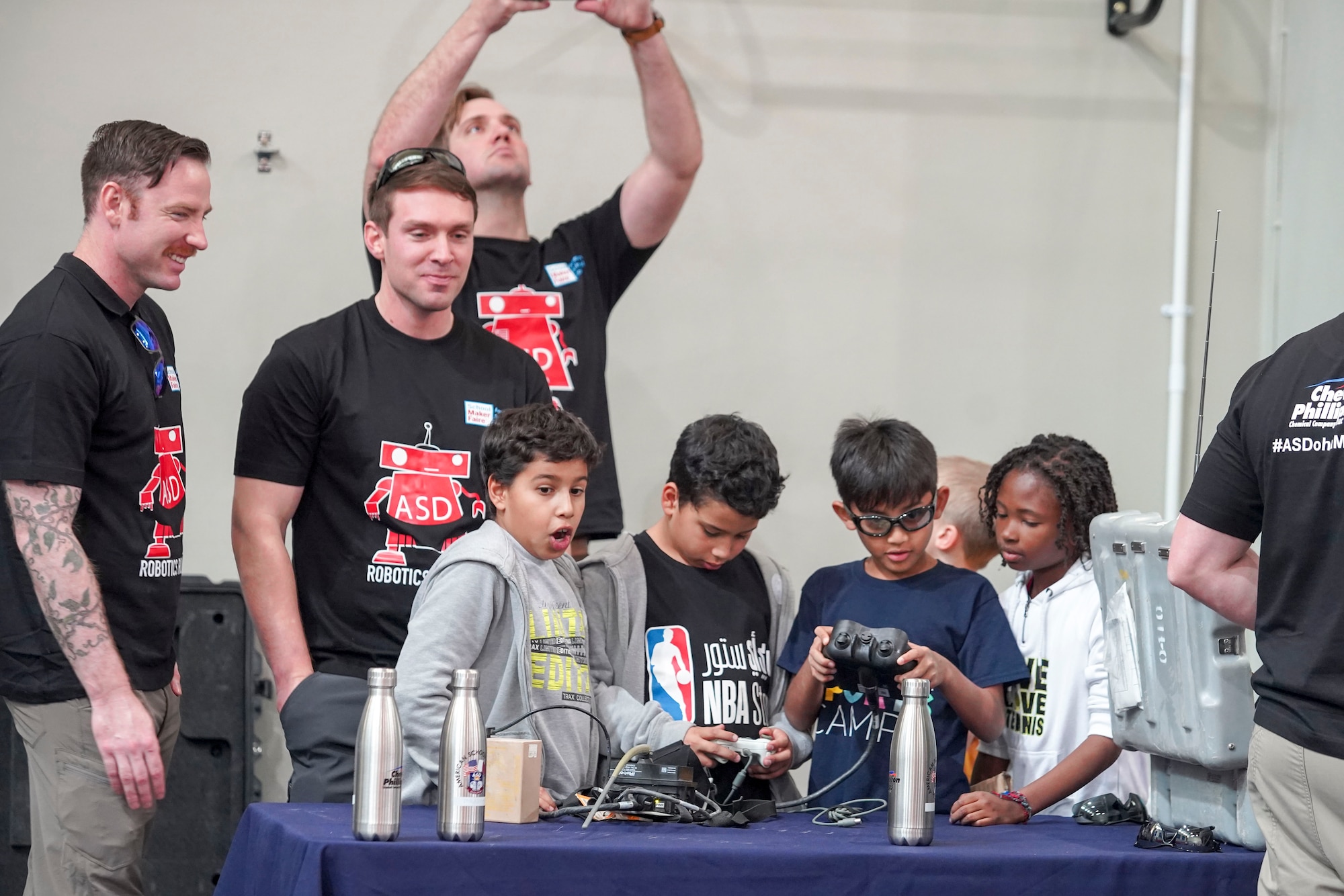 Airmen with 379th Expeditionary Civil Engineering Squadron explosive ordnance disposal team teach students how to operate a bomb defusal robot at American School of Doha’s Maker Faire in Doha, Qatar, on Jan. 25, 2020. EOD Airmen volunteers gave students attending the faire a hands-on experience driving the robots through an obstacle course where they were tasked with using a robot to grab a cone and stack it on another cone. (Courtesy Photo)