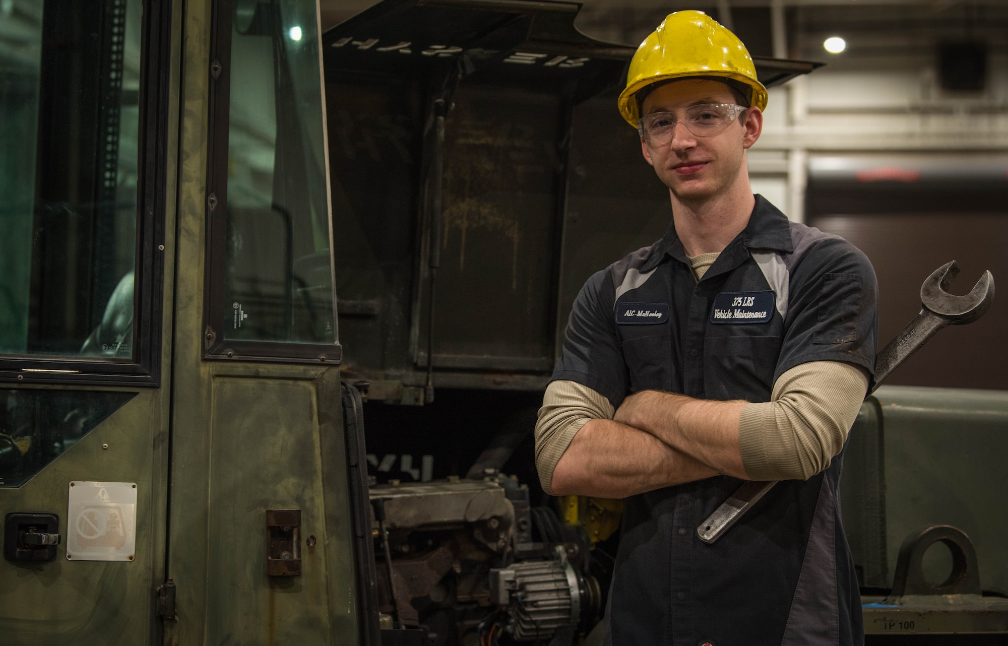 Vehicle maintainer poses in front of forklift.