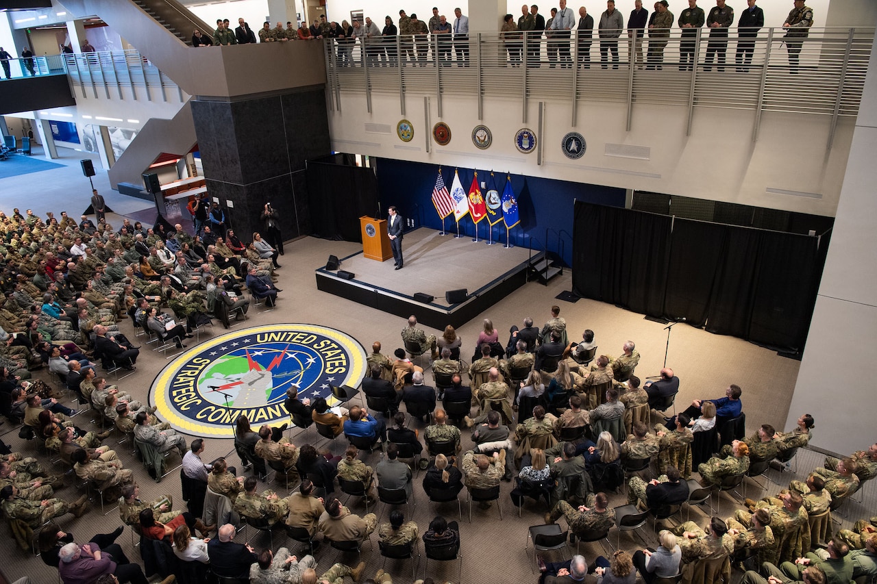 Defense Secretary Dr. Mark T. Esper stands on a stage speaking to an audience as seen from above.