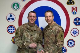 Brig. Gen. Howard Geck, right, commander, poses with Capt. Jordan Goldie, deputy comptroller, 103rd Expeditionary Sustainment Command, and his United States Department of Agriculture (USDA) Honor Award at Camp Arifjan, Kuwait, Feb. 21, 2020.