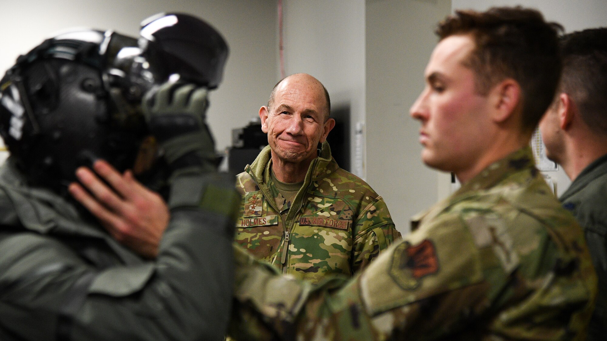 Gen. Mike Holmes, commander of Air Combat Command, watches as an Airman puts on a helmet.