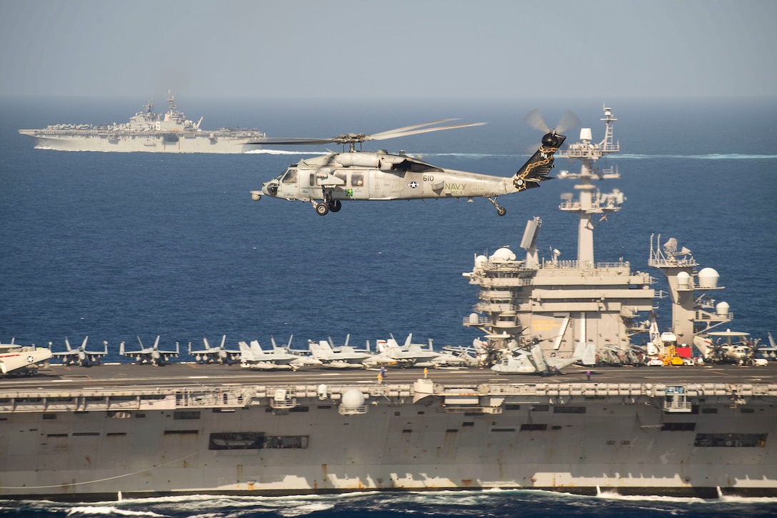 A helicopter flies next to two ships.