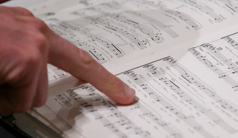 Master Sgt. Taylor Armstrong, U.S. Air Force Band Singing Sergeants conductor and vocalist, points to a sheet of music during a sound check before a concert in Redlands, Ca., Feb. 14, 2020. The ensemble performs a sound check before each concert to get a feel for the acoustics in the room and make sure everyone is in tune for their performance. (U.S. Air Force photo by Airman 1st Class Spencer Slocum)