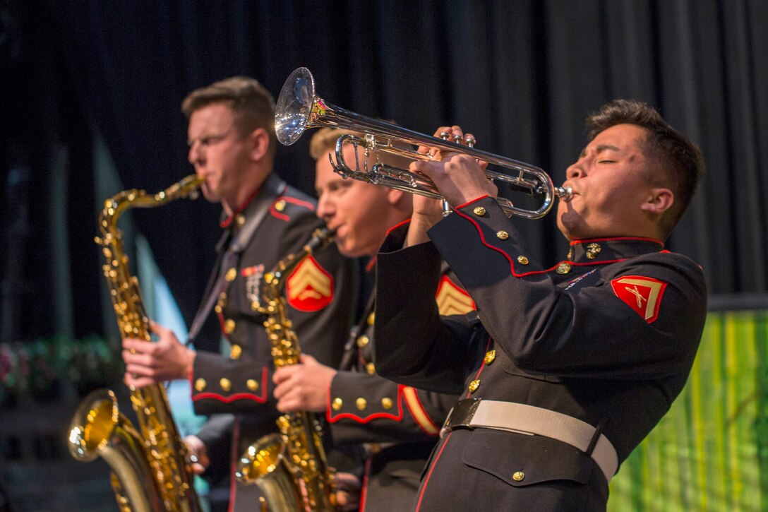 Three Marines play musical instruments in a concert.