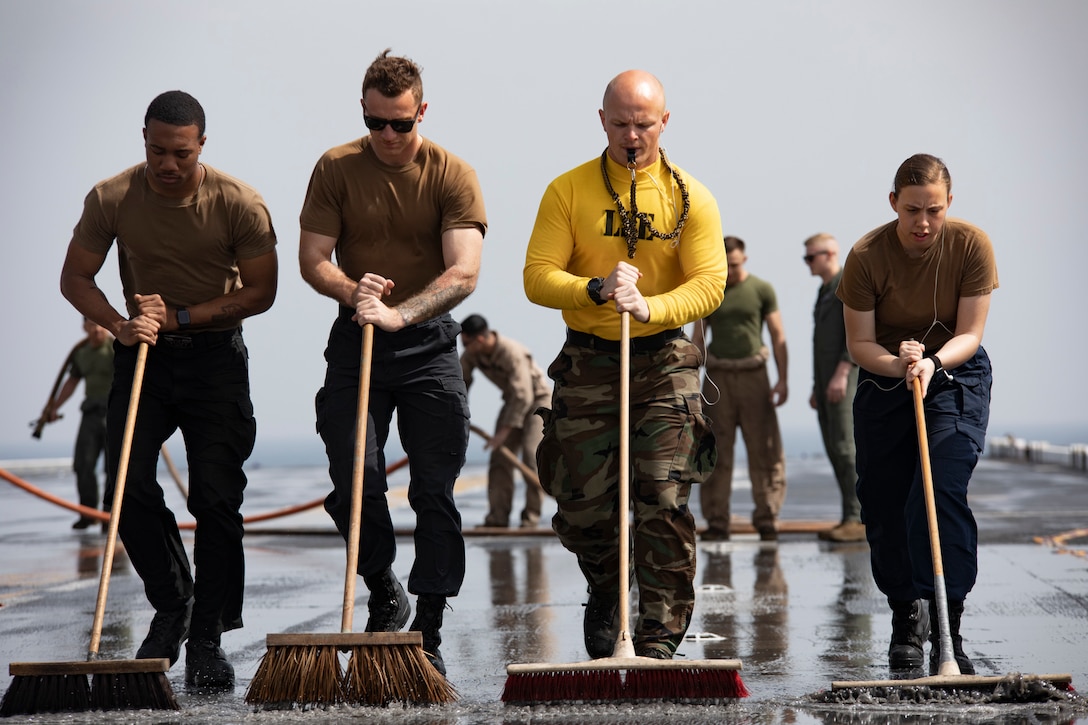 Sailors and Marines clean a ship.