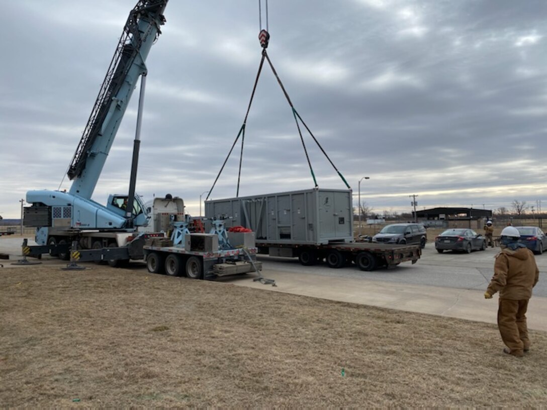 man watches as crane moves generator.