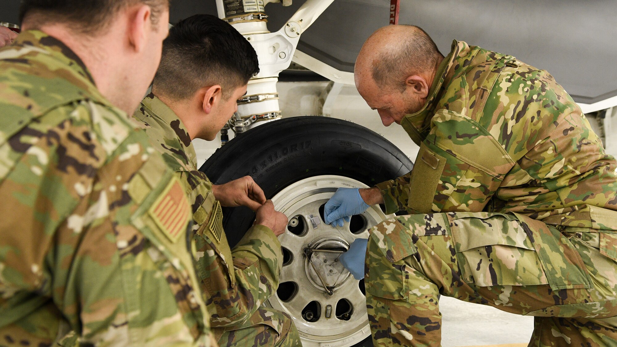 Gen. Mike Holmes, commander of Air Combat Command, and two other Airmen change a tire on an F-35 Lightning II.