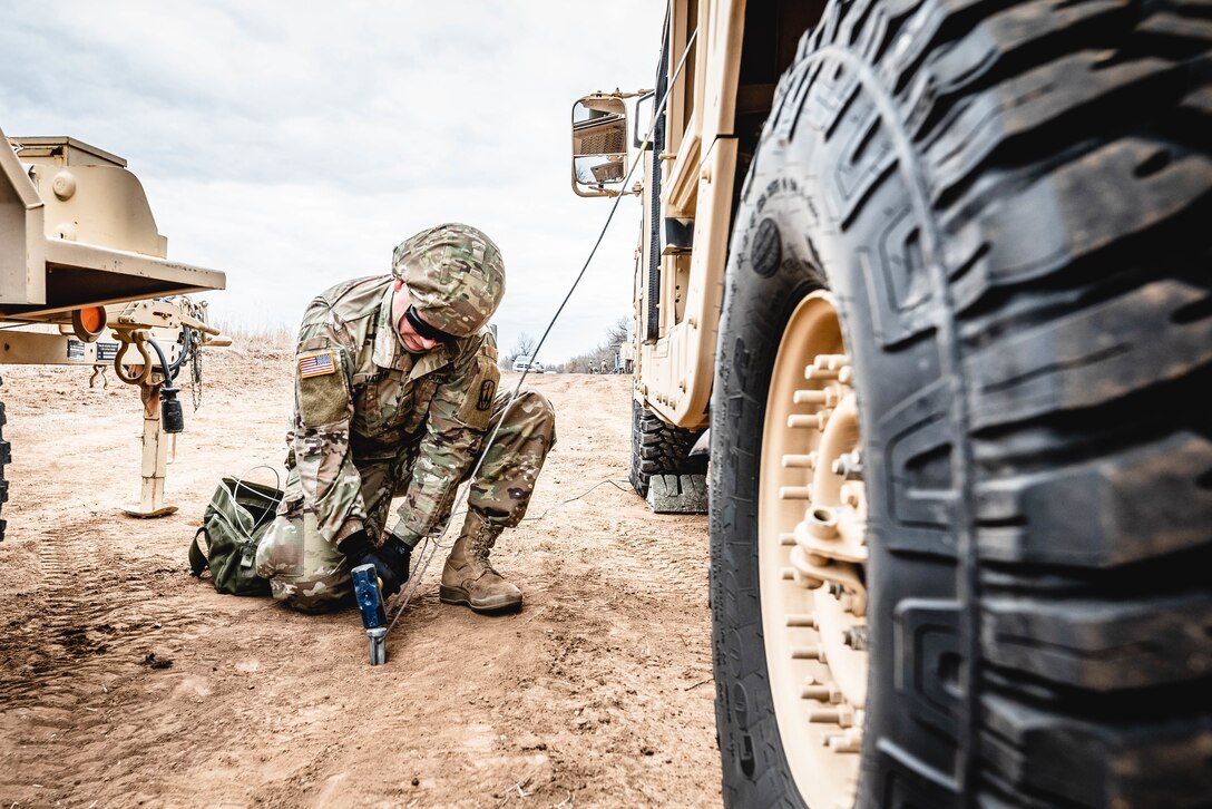 A soldier hammers a stake into the ground.