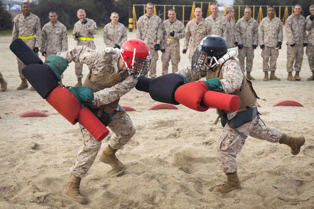 Two Marine Corps recruits fight each other using pugil sticks.