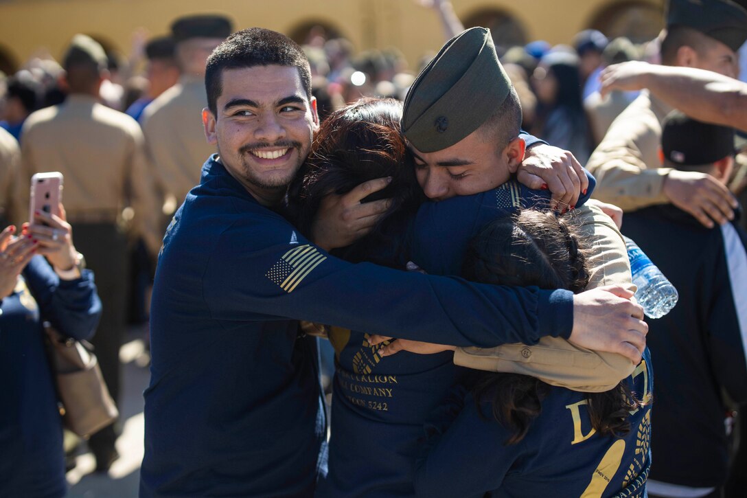A Marine hugs three people.