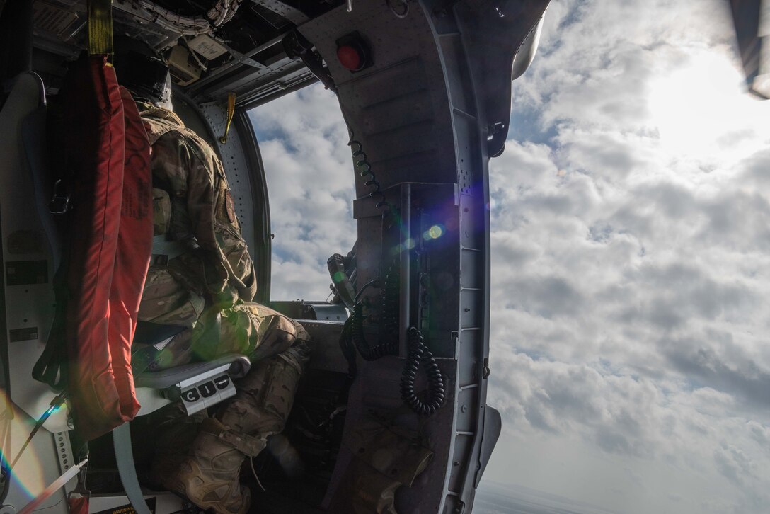 U.S. Air Force Tech. Sgt. Tyler Peterson, special mission aviator assigned to the 33rd Rescue Squadron, Kadena Air Base, Japan, looks out the gunner’s window aboard an HH-60G Pave Hawk during a combat search and rescue training mission Feb. 13, 2020, over the island of Okinawa. The HH-60G Pave Hawk is capable of performing peacetime operations such as civil search and rescue, emergency aeromedical evacuation, disaster relief, international aid and counter-drug activities. (U.S. Air Force photo taken by Senior Airman Cynthia Belío)