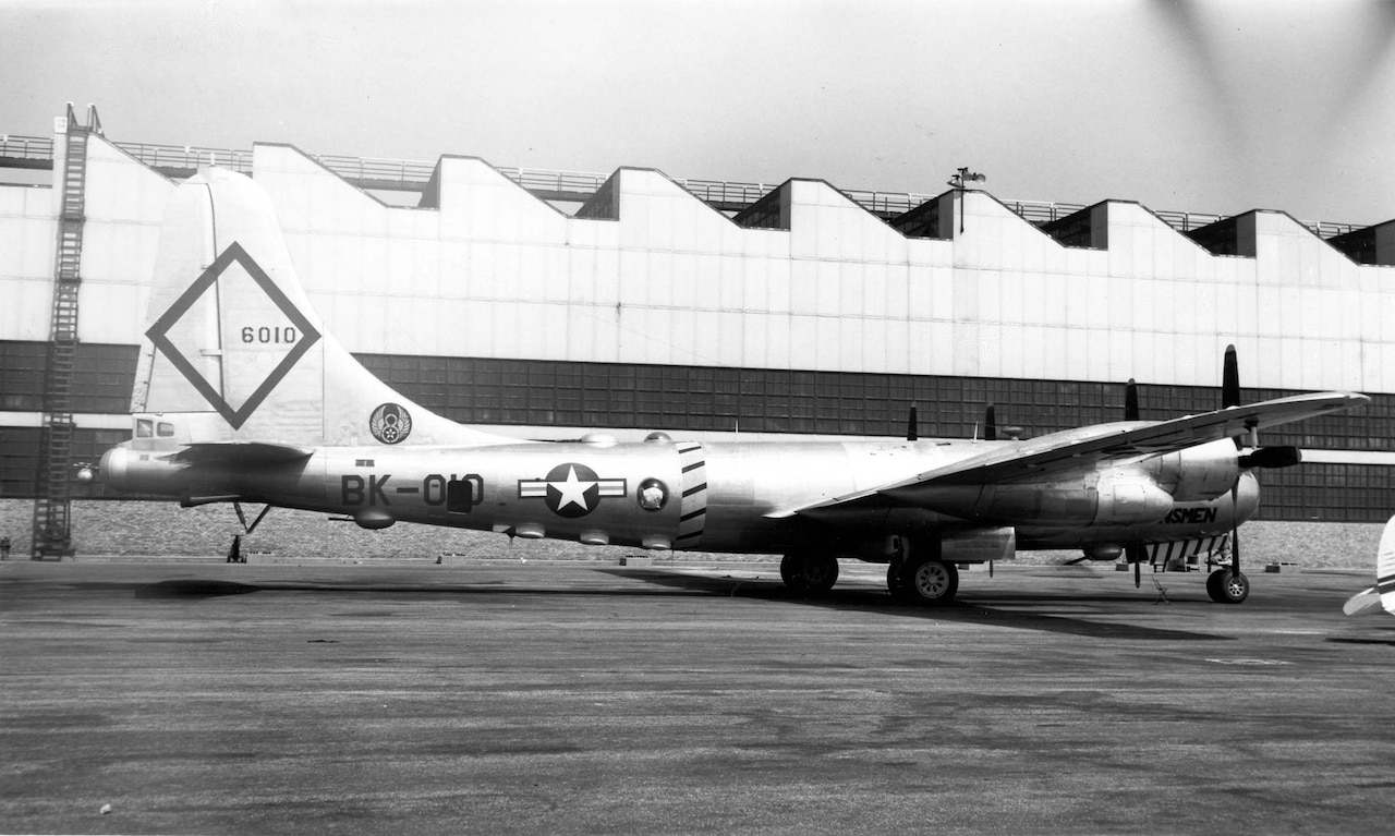 A 1940s-era bomber aircraft with the number 6010 on its tail sits on the tarmac.