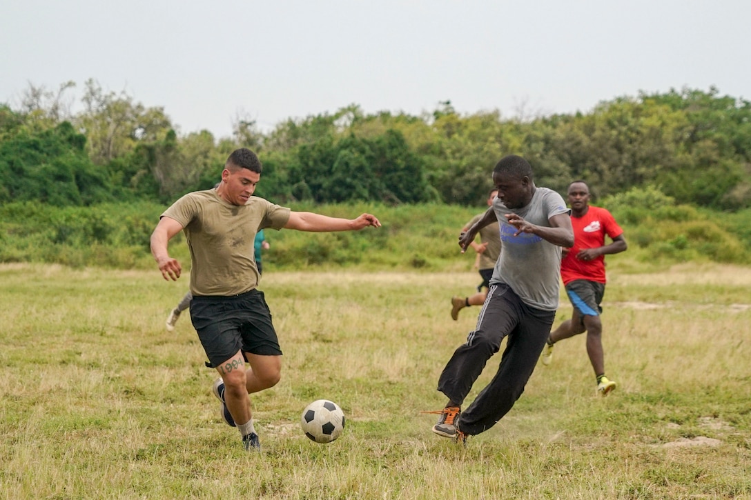 Service members in civilian clothes play soccer.