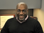 A man sits in a chair smiling for the camera.