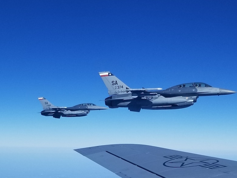 Two F-16 Fighting Falcon aircraft fly alongside a KC-135 Stratotanker aircraft.