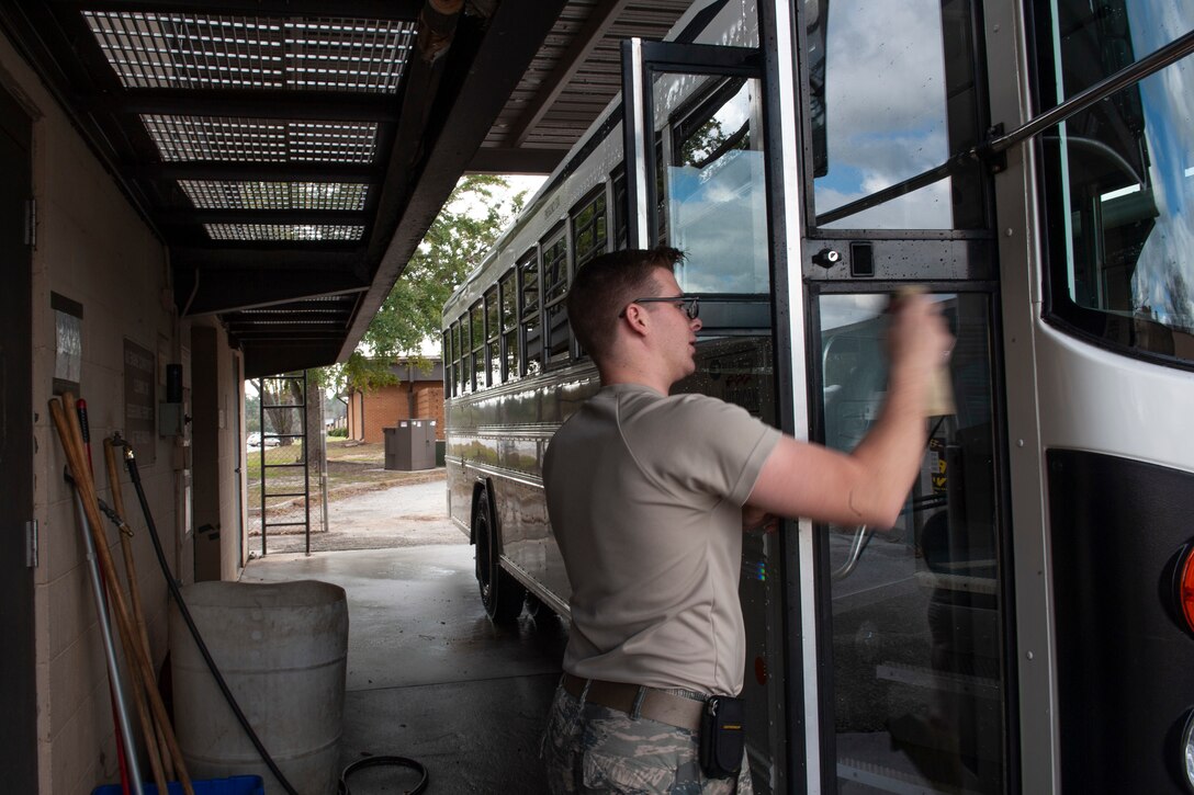 Photo of Airman cleaning bus windows