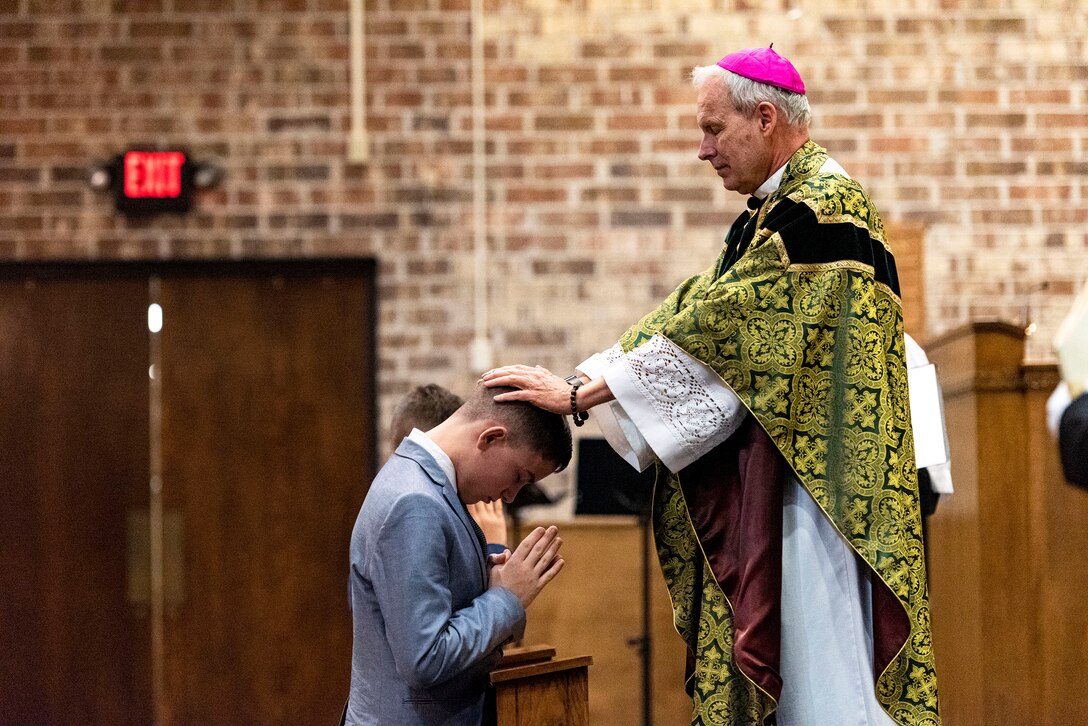 Photo of bishop laying on hands during a ceremony.