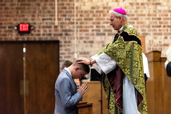 Photo of bishop laying on hands during a ceremony.