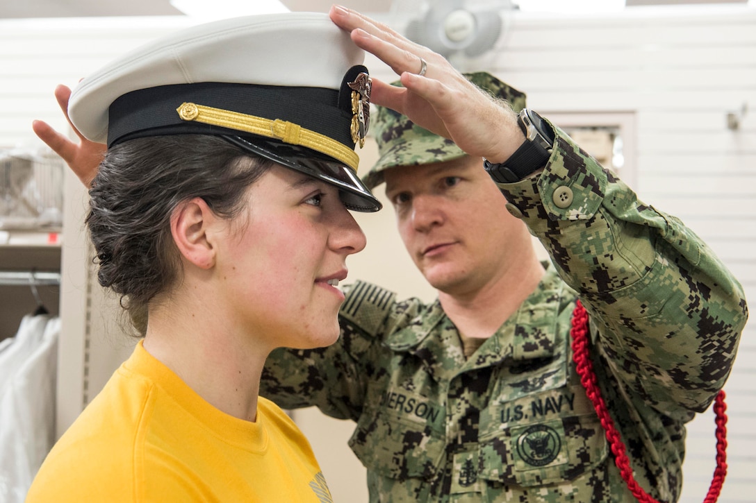 A sailor puts a cover on a student.