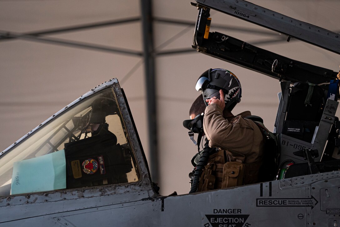 A photo of a pilot putting on a helmet
