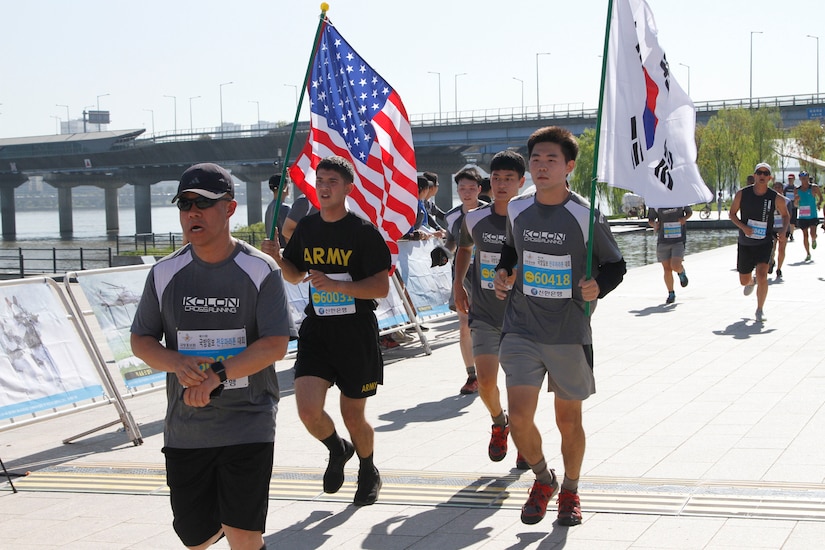 Runners take part in a race. Two runners carry a U.S. and South Korean flag.