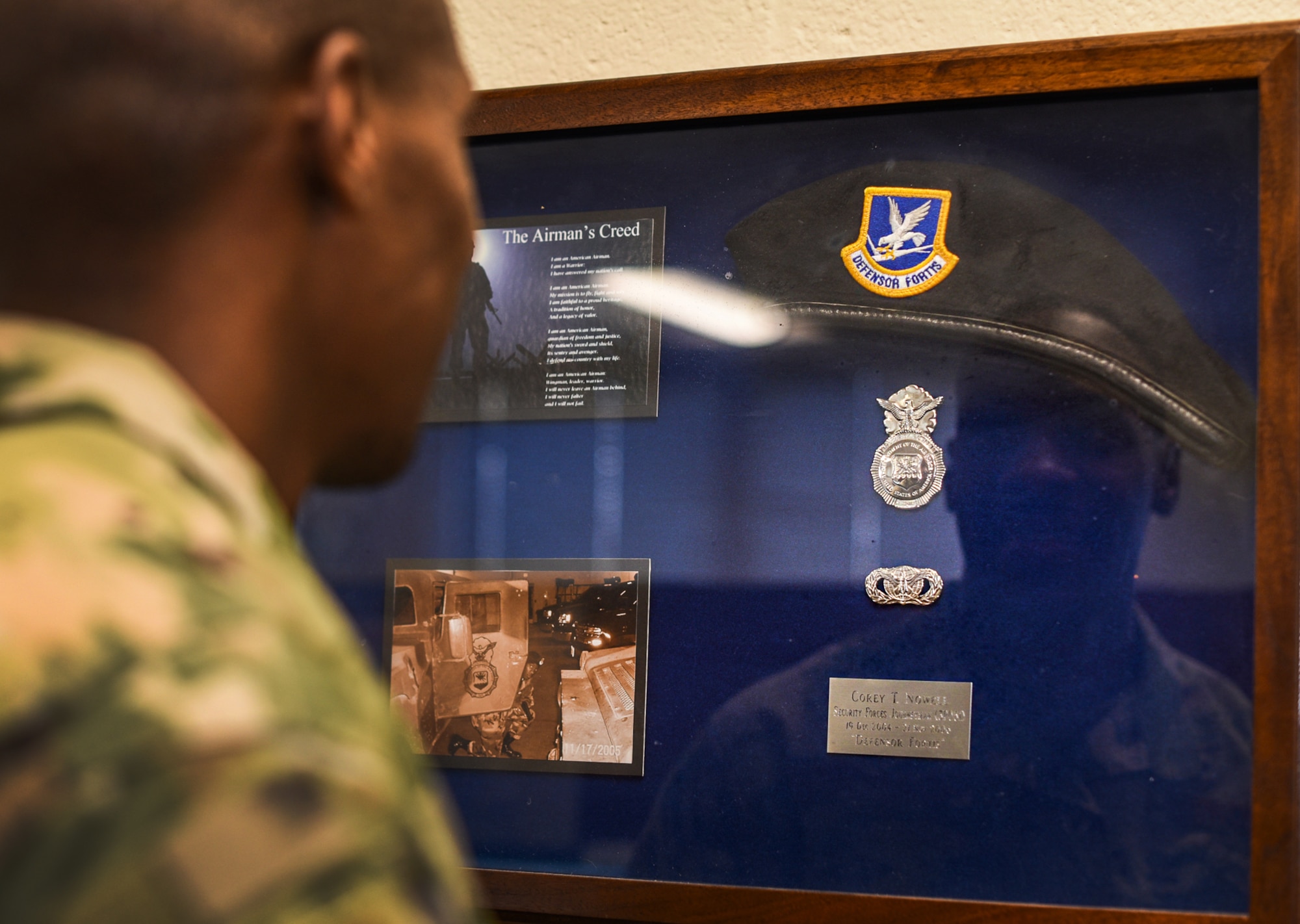 Tech. Sgt. Corey Nowell, noncommissioned officer in charge of movement support at the Joint Personal Property Shipping Office Northeast, is reflected in his security forces shadow box at Hanscom Air Force Base, Mass., Feb. 21. Nowell enlisted in the Air Force at 18 as a security forces defender, but retrained as a traffic manager following a car accident that resulted in a level-2 concussion. (U.S. Air Force photo by Mark Herlihy)