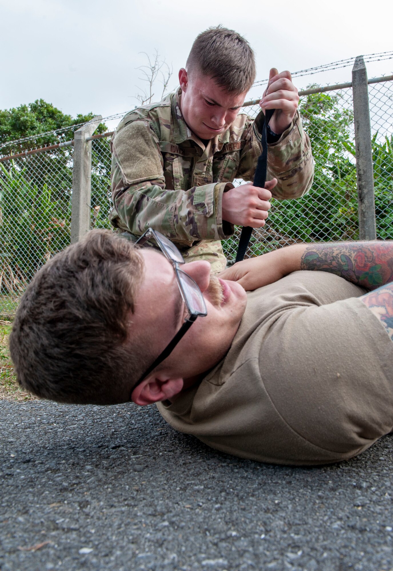 U.S. Air Force Airman 1st Class Kevin Kovach, 18th Security Forces Squadron response force leader, places a tourniquet on the simulated patient’s arm during the Defenders Challenge at Kadena Air Base, Japan, Feb. 13, 2020. This was one of several events participants had to overcome during the Defenders Challenge. The events varied from physical exercise, a three-mile run, to weapon assembly. (U.S. Air Force photo by Naoto Anazawa)