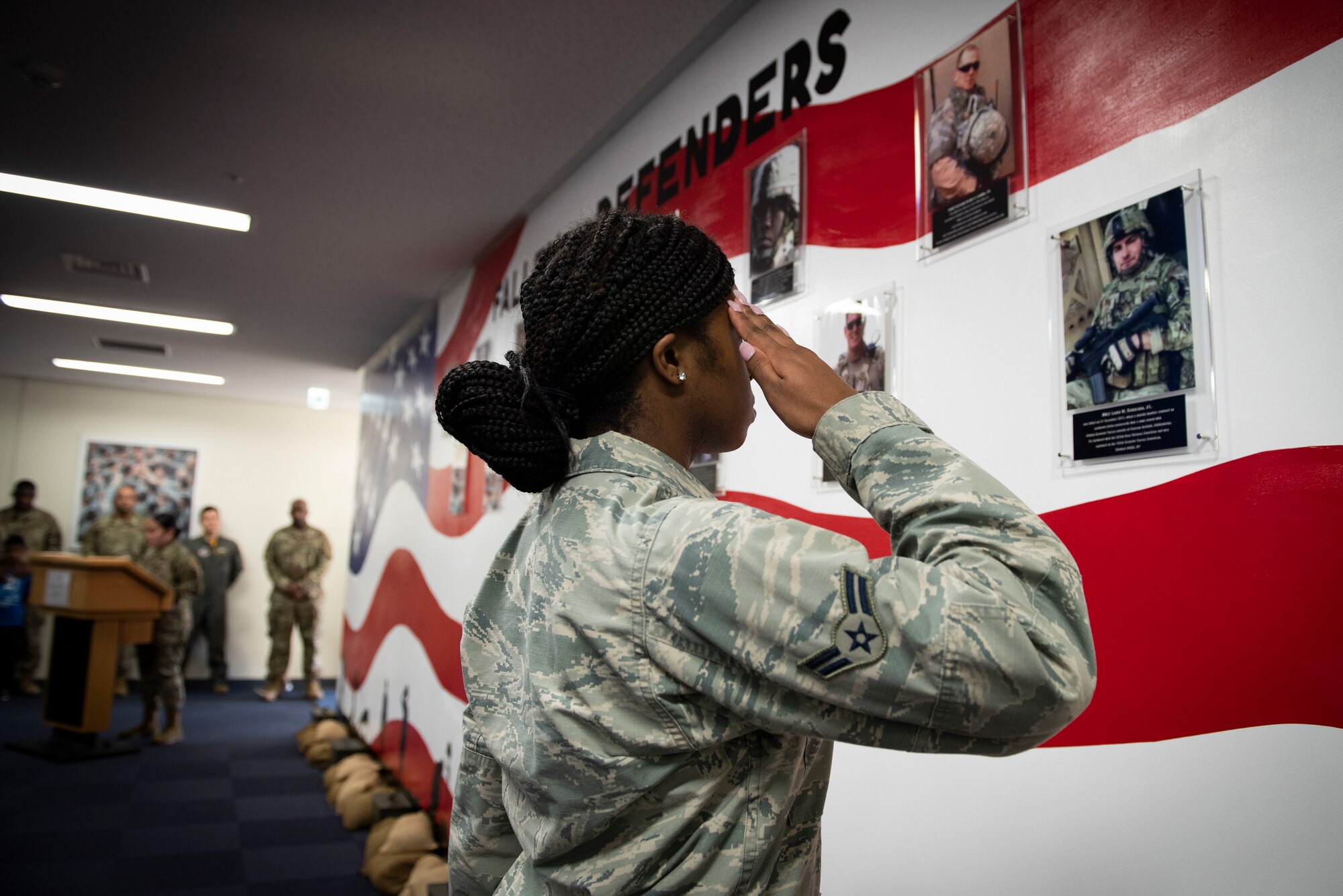Airman 1st Class Wanisha Spence, 374th Security Forces Squadron patrolman, salutes a photo of security forces airmen who fell in the line of duty, during a mural unveiling ceremony at Yokota Air Base, Japan, Feb. 21, 2020.