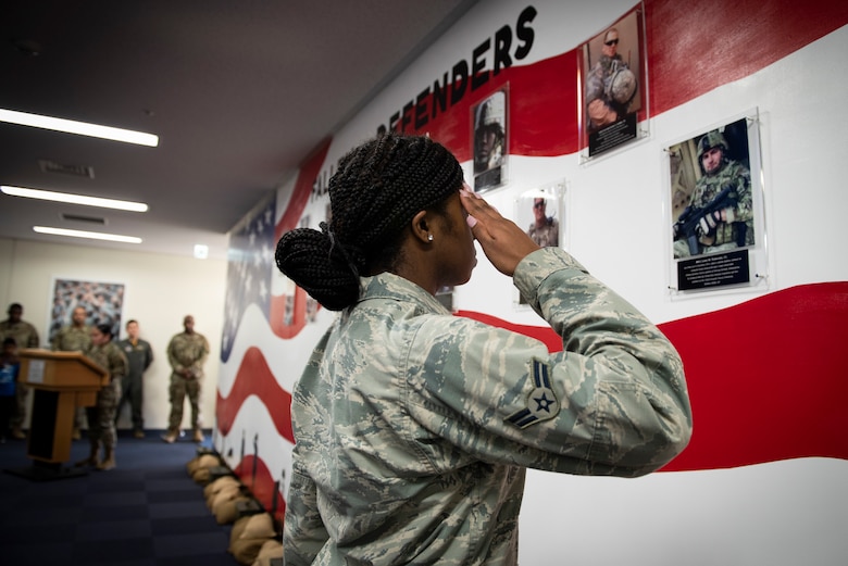 Airman 1st Class Wanisha Spence, 374th Security Forces Squadron patrolman, salutes a photo of security forces airmen who fell in the line of duty, during a mural unveiling ceremony at Yokota Air Base, Japan, Feb. 21, 2020.