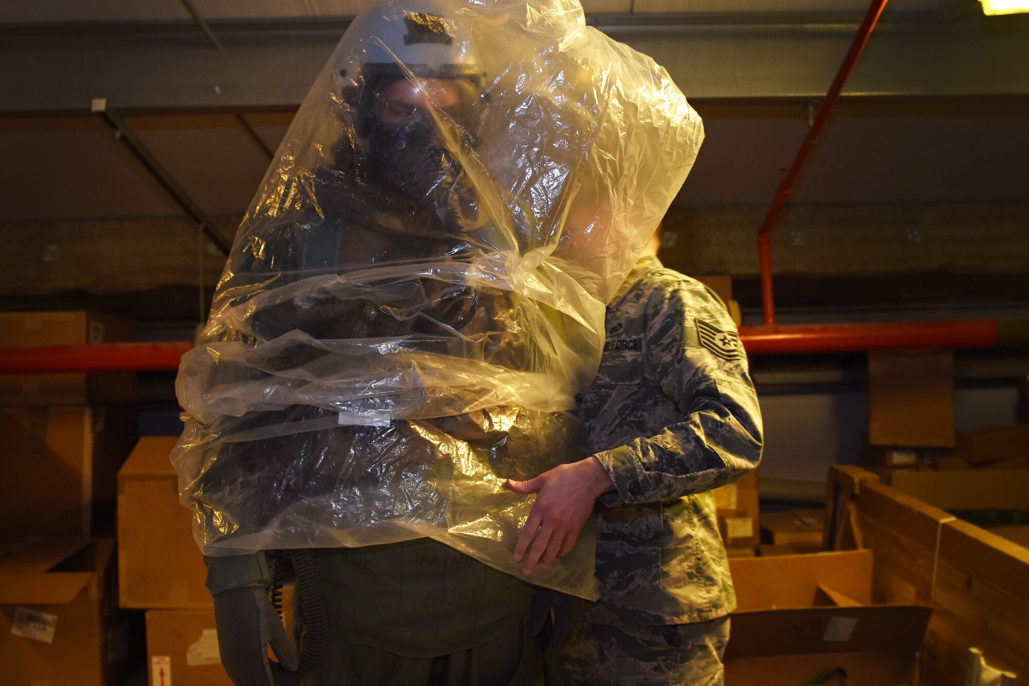 Tech. Sgt. David Vazquez Velez, 48th Fighter Wing Aircrew Flight Equipment, demonstrates the use of an over cape during an Aircrew Contamination Control Area training exercise at Royal Air Force Lakenheath, England, Feb. 21, 2020. The training is conducted to ensure pilots and weapons systems officers can maintain mission readiness under any adverse conditions.  (U.S. Air Force photo by Airman 1st Class Jessi Monte)