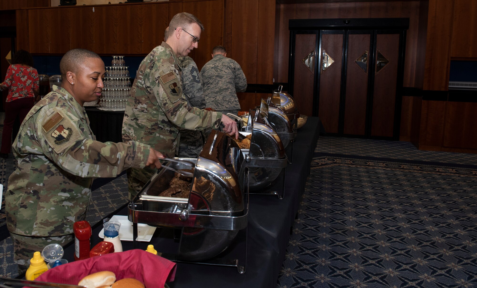 U.S. Air Force Chief Master Sgt. Cheronica Blandburg, 52nd Fighter Wing Munitions Maintenance Group superintendent and U.S. Air Force Col. Greg Buckner, 52nd FW MMG commander, serve themselves food during the Black History Month Luncheon at Spangdahlem Air Base, Germany, Feb. 24, 2020. During the luncheon participants viewed a short video featuring African-American icons and abolitionists. (U.S. Air Force photo by Airman 1st Class Alison Stewart)