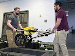 Dean Edwards, left, and Juan Olguin-Martinez, biomedical equipment technicians for USAMMA’s Medical Maintenance Operations Division, unload a mobile X-ray machine for inspection Feb. 12, 2020, while servicing medical equipment for the Army National Guard’s 104th Area Support Medical Company at Camp Fretterd Military Reservation near Reisterstown, Md.