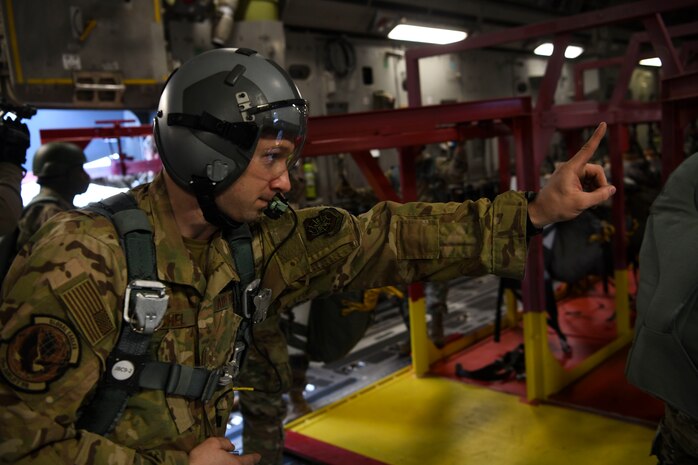 Staff Sgt Johnathan Fishel, a C-17 Globemaster III loadmaster assigned to the 15th Airlift Squadron at Joint Base Charleston, S.C., gives a jump master the, “one minute before drop” hand sign over Pope Army Airfield, N.C., Feb. 20, 2020.