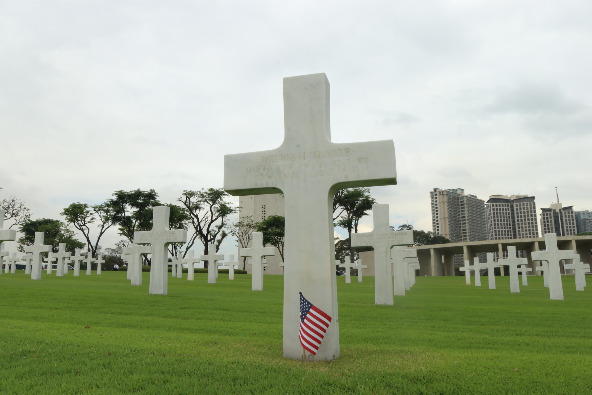 An American flag sits in the ground in front of a gravestone of a fallen service member of the 317th Troop Carrier Group at the Manila American Cemetery in Manila, Philippines, Feb. 17, 2020.