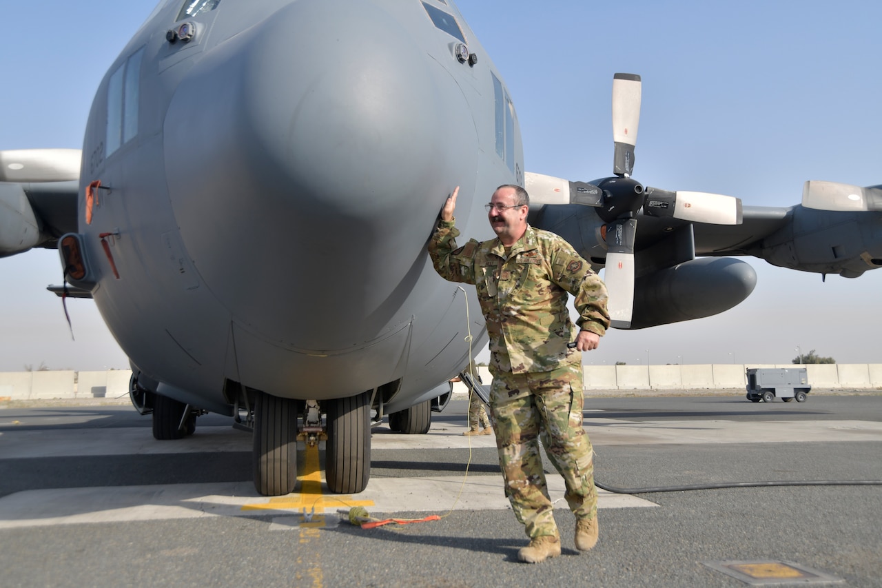 An airman touches the nose of an airplane.