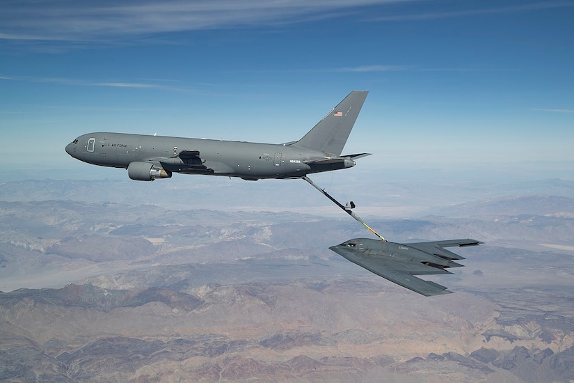 Large tanker jet refuels smaller bomber in the air.